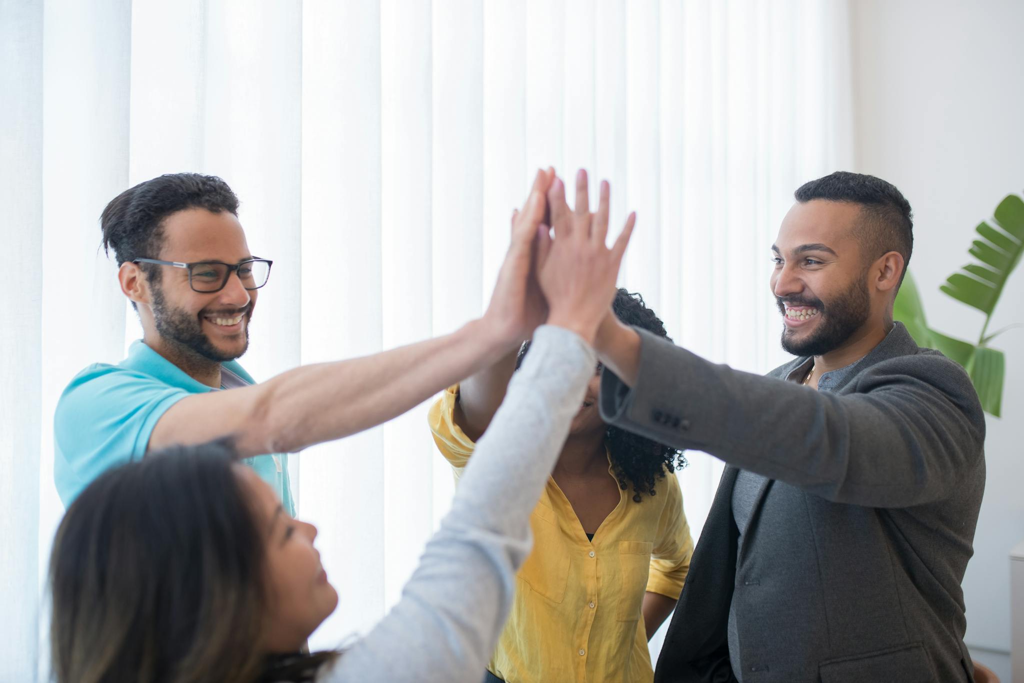 Happy diverse team in a bright office celebrating success with a high five.